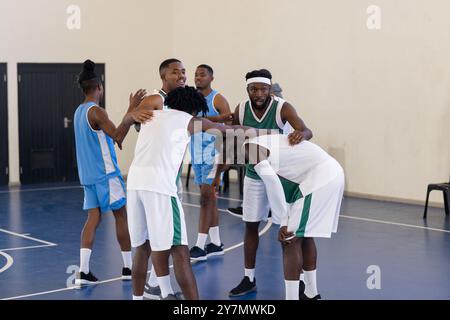 Giocatori afroamericani di basket che si accoccolano sul campo, preparandosi per una discussione sulla strategia di gioco Foto Stock