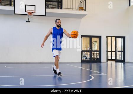 Dribbling di basket, uomo che pratica sul campo al coperto, concentrandosi sulle abilità Foto Stock