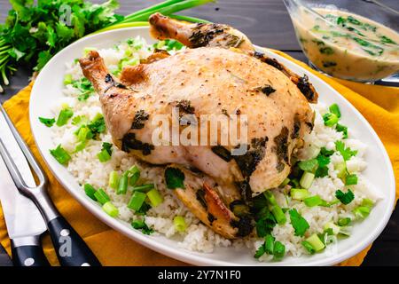 Pollo arrosto con latte di cocco e citronella servito sul riso: Pollo intero servito su un piatto con riso al gelsomino, scaldini e coriandolo Foto Stock