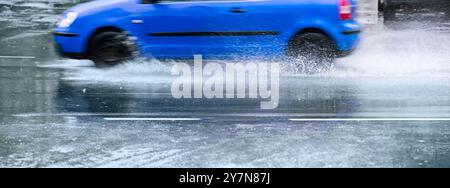 un'auto blu spruzza su strade allagate dopo la pioggia. vista panoramica. Foto Stock