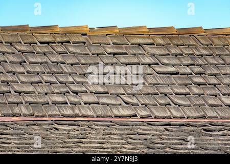 Una vista ravvicinata di un vecchio tetto in legno di tegole, con molte delle tegole che appaiono intemprate e leggermente deformate Foto Stock