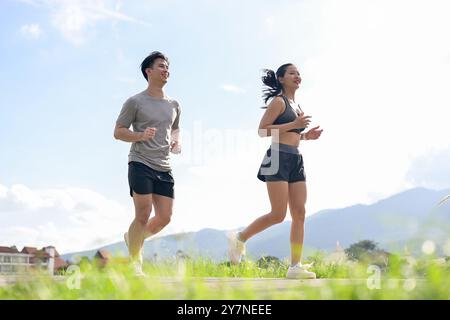 Una coppia asiatica attiva e sportiva di abbigliamento sportivo fa jogging o corre insieme nel parco al mattino. fidanzata e fidanzato, stile di vita sano, w Foto Stock