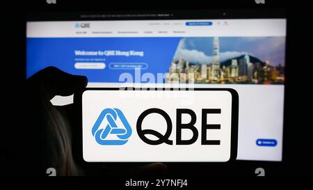 Germania. 26 settembre 2024. In questa immagine, una persona ha in mano un cellulare con il logo della società australiana QBE Insurance Group Limited davanti alla pagina Web aziendale. Credito: SOPA Images Limited/Alamy Live News Foto Stock