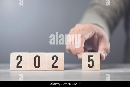 Hand sostituisce "2024" con "2025" utilizzando blocchi numerici, simboleggiando la transizione verso il nuovo anno, rappresentando il cambiamento, il progresso e i PA in corso Foto Stock