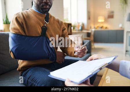 Primo piano di Black Man con braccio Sling firma modulo medico Foto Stock