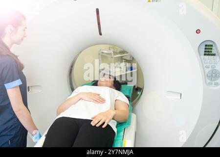 Il tecnico di scansione TC si affaccia sul paziente nello scanner di tomografia computerizzata durante la preparazione della procedura. Paziente donna che entra nello scanner TC. Foto Stock