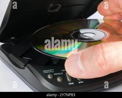 Primo piano della mano di un uomo che inserisce un CD in un lettore CD portatile. Foto Stock