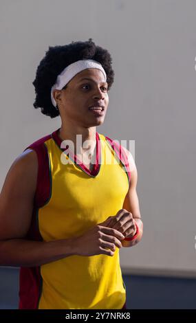 Indossando l'archetto, il giocatore di basket in maglia gialla in piedi sul campo Foto Stock