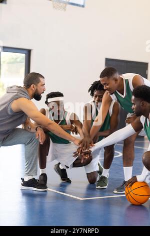 Allenatore di pallacanestro e squadra che si accoccolano sul campo, preparandosi alla strategia di gioco Foto Stock