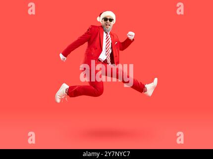 Un uomo entusiasta e positivo con il cappello di babbo natale che corre veloce e si affretta agli sconti per l'anno nuovo. Foto Stock