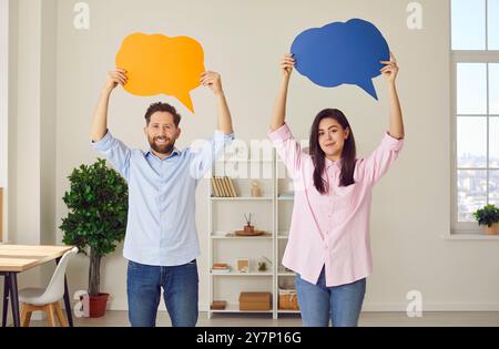 Coppia in piedi a casa con vuote e colorate bolle di discorso sopra la testa per i pensieri. Foto Stock