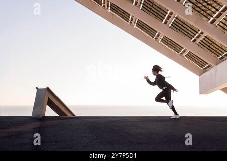 atleta in abbigliamento sportivo che corre con le braccia alzate Foto Stock