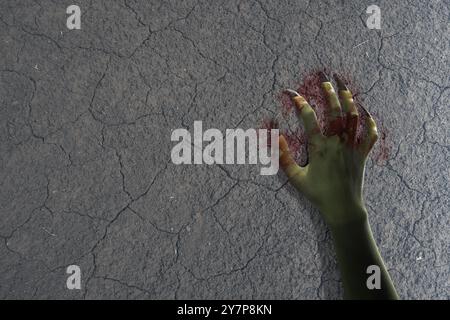 La mano della strega con il lungo artiglio dell'unghia è su un terreno. La mano di colore è verde e ricoperta di sangue. Malvagio, zombie o mano mostro. La scena è spaventosa e cre Foto Stock