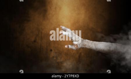 Mano della mamma in bende che si alzano dalla nebbia con uno sfondo scuro. La scena è oscura e spaventosa. La mano sembra essere un diavolo, un male, un satana, uno zombie o un Foto Stock