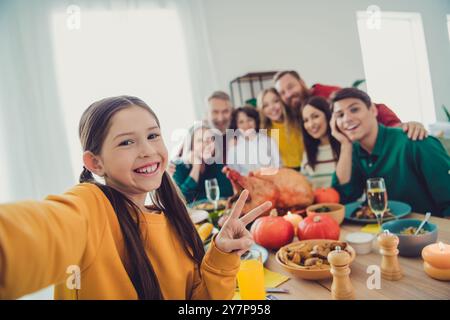 Foto di una riunione di famiglia piena e allegra scatta una foto con il cartello a V che mangia la cena del Ringraziamento buon umore divertirsi a casa in casa Foto Stock