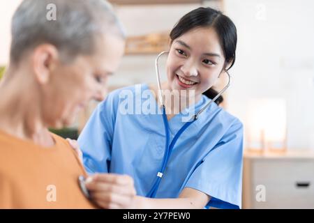 Professionista sanitario sorridente visita Senior a casa, fornendo assistenza medica e supporto Foto Stock