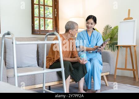 Professionista sanitario visita Senior a domicilio, fornendo assistenza e supporto in un ambiente confortevole da salotto Foto Stock