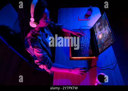 Foto ad angolo alto di una giovane donna che gioca a videogame mouse per laptop esport neon light night Apartment indoor Foto Stock