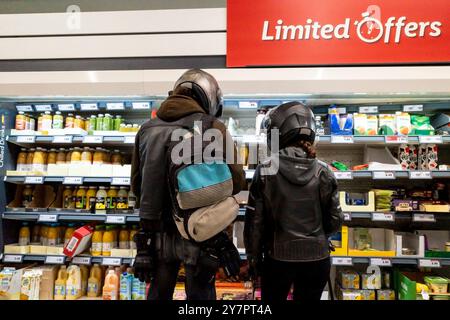 Due acquirenti clienti persone che indossano caschi da crash persone che fanno acquisti all'interno di un negozio Lidl in Inghilterra nel Regno Unito. Foto Stock