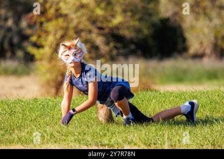 La giovane bambina indossa la maschera pelosa del gatto divertiti a giocare all'aperto nel parco di Forest Street. I bambini hanno un carattere di animali selvatici alla moda Foto Stock