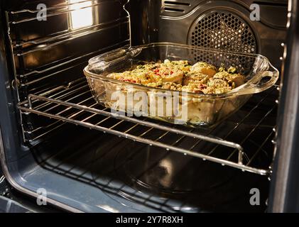 Involtini di verdure freschi cotti in un piatto di vetro all'interno di un forno, seguiti dal risultato finale panini dorati con semi di sesamo. Foto Stock