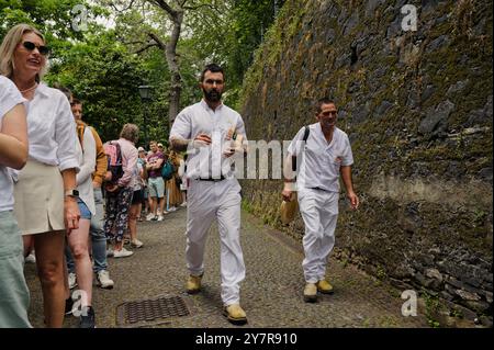 I Carreiros camminano velocemente attraverso una fila di turisti, pronti per la loro prossima corsa giù per la collina Foto Stock