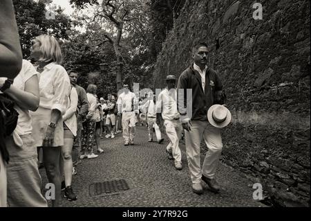 Monocromatico di carreiros che si fanno strada attraverso una fila di turisti, pronti per la prossima discesa Foto Stock