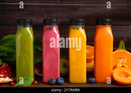 Bottiglie di vetro di frullati gustosi e diversi prodotti su un tavolo di legno Foto Stock