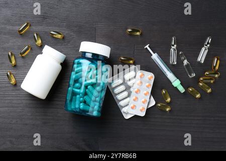 Farmacista. Diverse pillole, bottiglie di plastica, siringa e fiale su un tavolo in legno grigio, piatto Foto Stock