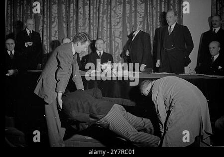 LE EFFIGIE DELL'ARMADIO TAUS TUSSAUD SONO STATE DISTRUTTE 18.2,54. Le figure di Sir Winston Churchill e di altri tre ministri di gabinetto della mostra di Madame Tussaud, Londra, sono state distrutte da un uomo con un martello oggi. Valgono circa 1.000 sterline. La foto INP mostra il signor Stan Wismark, l'artista dello studio, e uno degli assistenti della mostra spostano il corpo in cera del signor Thornycroft, che è stato danneggiato oggi. Foto di Joe Waldorf 74630/MB International News Photos. Foto Stock