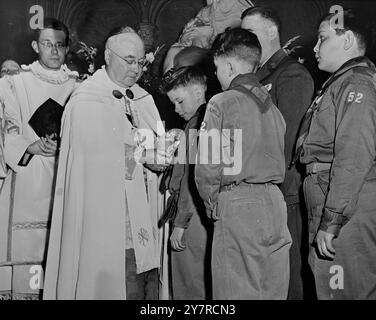 I RAGAZZI SCOUT CATTOLICI RICEVONO IL PIÙ ALTO RICONOSCIMENTO 9,2.54. Il cardinale Francis Spellman, arcivescovo di New York, ha segnato l'apertura della Boy Scout Week conferendo la ad altare dei Cross, la più alta decorazione per un Boy Scout cattolico, su 228 ragazzi. La foto di N.P. mostra il cardinale Spellman che fissa la croce su James Patrick Daniels, 12 anni, nei panni di Leonard Hoffman, District Scout Executive del Bronx, e i boy scout guardano. A sinistra c'è il reverendo Thomas Gallagher. 1/MB/74442 International News Photo. Foto Stock