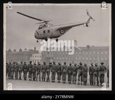 Hanno visto il Duca volare partire. - Londra: Stando in linea, le truppe coloniali guardano un elicottero che trasporta il Duca di Edimburgo decollare dalla caserma di Woolwich dopo la sua ispezione delle truppe dell'incoronazione. L'aereo sospeso utilizzato dal Duca per il secondo giorno successivo stava tornando a Buckingham Palace per atterrare sul prato di Palace da dove era decollato stamattina. 27 maggio 1953. Planet News. Foto Stock