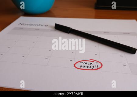 Calendario di novembre su una scrivania, con l'ultimo venerdì del mese cerchiato in rosso. Al suo interno ci sono scritte le parole Black Friday. Foto Stock