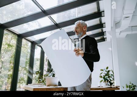 Ingegnere maturo concentrato che esamina il progetto mentre si trova nell'ufficio creativo Foto Stock