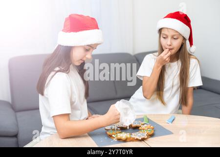 Due ragazze, sorelle, preparano biscotti di Natale in cucina e giocano in giro. Natale, Capodanno Foto Stock