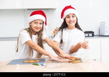 Due ragazze, sorelle, preparano biscotti di Natale in cucina e giocano in giro. Natale, Capodanno Foto Stock