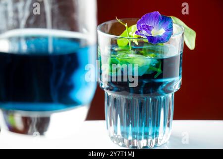 Bicchiere di tè viola o doppio fiore di pisello farcito isolato su sfondo arancione Foto Stock