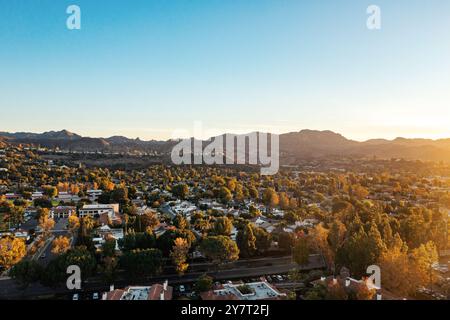 Si tratta di una prospettiva aerea mozzafiato che mostra una graziosa area residenziale con maestose montagne che incombono sullo sfondo durante un vivace sole Foto Stock