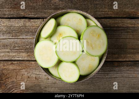 Zucchine appena tagliate nel recipiente su un tavolo di legno, vista dall'alto Foto Stock