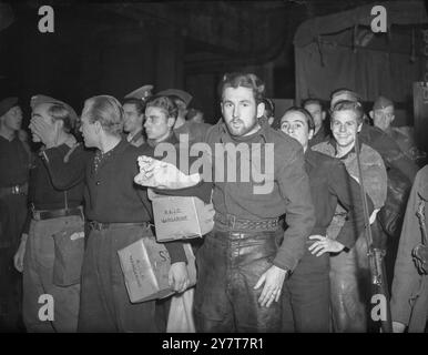 NAZISTI IN LONDONPhoto mostra:- una volta era "pistole prima del burro", ora questi giovani nazisti, disinteressati, preoccupati, allegri e - in un caso - timidi, sono felici di usare le scatole di margarina R.A.S.C. per tenere i loro pochi averi mentre vengono scortati lungo la piattaforma di una stazione di Londra, a bordo di un treno che li porterà in un campo di prigionia. 23 ottobre 1943 Foto Stock
