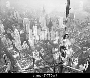 PIÙ IN ALTO DEI GRATTACIELI, chi ha i nervi abbastanza forti può guardare in basso anche i grattacieli massicci di New York. Un uomo per il quale non esiste un'altezza " gigante " è Andrew D. Vernon di Brooklyn, New York bridgeman della U.S. Steels American Bridge Company - visto con la sezione Midtown della città che si è diffusa davanti a lui mentre lavora su un'antenna televisiva temporanea in cima all'Empire State Building, l'edificio più alto del mondo, alto 1.250 metri. Vernon è una delle ventidue operaie siderurgiche strutturali impegnate in uno dei lavori più spettacolari mai intrapresi nel campo delle costruzioni siderurgiche: La c Foto Stock