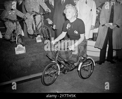 "TRIAL TURN" DI GRACIE Lancashire comica Gracie Fields è pronta per una prova mentre testa un triciclo per bambini al 25° Salone Internazionale di ciclismo e motociclismo di Earls Cour, Londra, oggi. Gracie era in visita allo spettacolo per scegliere i cicli per i bambini nell'orfanotrofio Gracie Fields a Peacehaven, non ha lasciato nulla di intentato nella sua ricerca dei modelli giusti. 21 ottobre 1949 Foto Stock