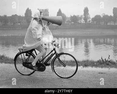 IL CAPITANO SI COPRE con un mantello impermeabile per proteggerla dalla pioggia, il mobile ' altoparlante' ANNE RUSHOLME di York pedala lungo il sentiero della città a Chiswick, Londra. Capitano della London University Rowing Girls , viene vista mentre impartisce istruzioni al suo equipaggio attraverso un megafono durante le esercitazioni sul Tamigi . 22 ottobre 1949 Foto Stock