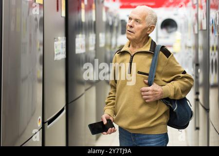Pensionato Senor MAN che acquista un frigorifero nello showroom del negozio di elettrodomestici Foto Stock