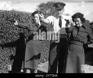 Thorney Island , Hampshire : Squadron leader Churton , Royal Air Force Regiment , of Headquarters Fighter Command , Stanmore , Middlesex , dà alcuni suggerimenti su come sparare revolver a Jean Winter di Rosyth, Scozia. La pratica delle armi fa parte dell'addestramento dei membri del Womens Observer Corps , che vanno in volo e si dedicano all'osservazione di aerei, mentre frequentano il campo estivo qui del Royal Observer Corps .7 settembre 1949 Foto Stock