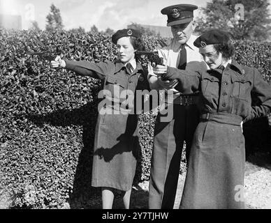 Thorney Island , Hampshire : Squadron leader Churton , Royal Air Force Regiment , of Headquarters Fighter Command , Stanmore , Middlesex , dà alcuni suggerimenti su come sparare revolver a Jean Winter di Rosyth, Scozia. La pratica delle armi fa parte dell'addestramento dei membri del Womens Observer Corps , che vanno in volo e si dedicano all'osservazione di aerei, mentre frequentano il campo estivo qui del Royal Observer Corps .7 settembre 1949 Foto Stock