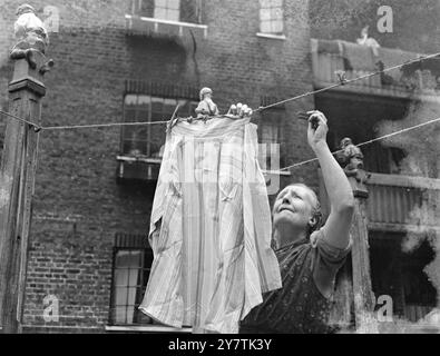 " Fairies " guarda dove si trovano i vestiti. Londra: Le casalinghe che vivono nel blocco di appartamenti a Somers Town , St Pancras , Londra trascorrono gran parte del loro tempo in 'Fairyland' il giorno del lavaggio. Nei cortili di dove vivono si trovano cartoni di pali dai quali sono sospese le linee d'abbigliamento , e in cima a ciascuno di questi posti si trovano piccole figure di personaggi del paese delle fate e della filastrocca . Le linee di vestiti da cui il lavaggio è appeso per essere dred , irradiate da una colonna centrale , e con questo semplice mezzo una grande quantità di lavaggio può essere asciugata in un piccolo spazio. Spettacoli fotografici: Una casa Foto Stock