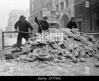 Westminster affronta la neve una grande campagna di sgombero della neve è stata avviata dal Westminster City Council. Hanno una flotta di autocarri che rimuovono la neve dalle strade fino ai canali di scolo strategicamente collocati , dove la neve viene ' scaricata '. Le strade principali vengono prima sgomberate quelle meno importanti verranno trattate in seguito, a meno che non si verifichi un disgelo. Spettacoli fotografici: I dipendenti del Westminster Council spalancano una "montagna" di neve in uno scarico nel centro commerciale Pall. 8 marzo 1947 Foto Stock