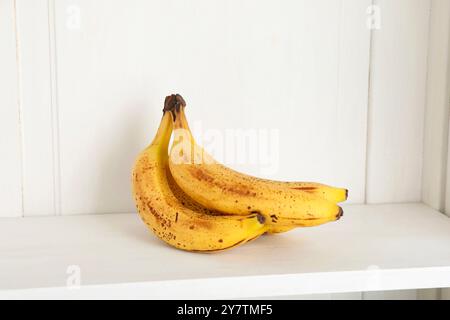 Mucchio di banane mature con macchie scure sullo scaffale Foto Stock