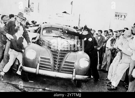 Film Stars crash studio picket linesPhoto Show: Picchetti affrettano un'auto nel tentativo di spingerla oltre mentre il conducente cerca di passare attraverso le linee del picchetto al Warner Brothers Studio di Burbank , California . Le linee di picchetto sono state poste fuori da dieci studi dai membri della suggestiva Conferenza dei sindacati di Studio in segno di protesta contro quello che è stato definito un " blocco dei produttori ". Oltre alla questione dell' aumento salariale , vi è disaccordo sul fatto che carpentieri afflizzati dalla CSU o creatori di set appartenenti alla AFL ( American Federation of Labour ) costruiscano set cinematografici . 29 settembre 1946 Foto Stock